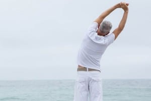 men's health - man stretching on the beach